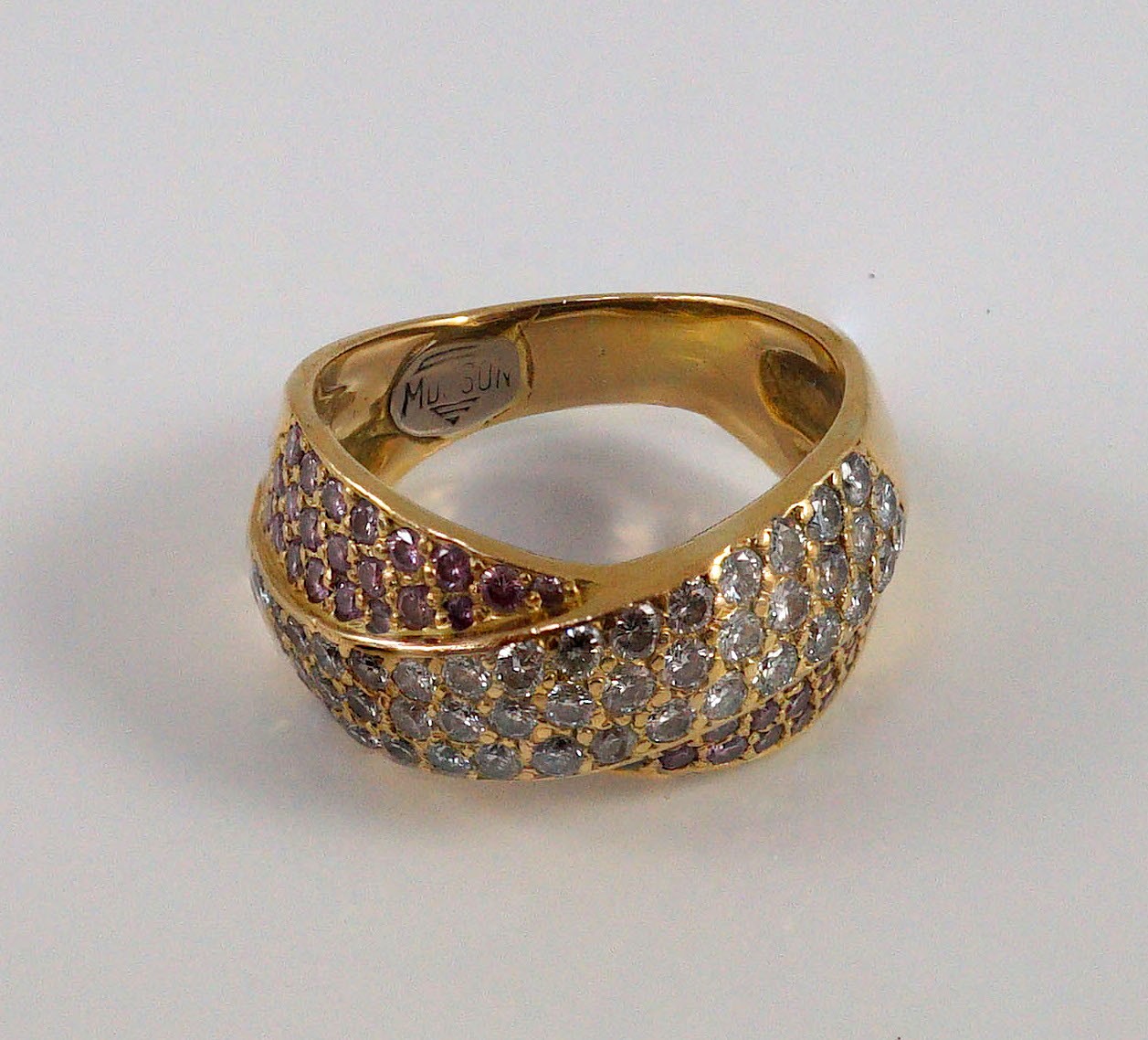 A modern gold (tests as 18ct), pink and white pave set diamond cross over ring, by Musson
